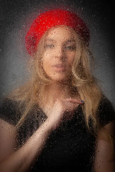 Blondes Mädchen Mit Roter Baskenmütze Hinter Feuchtem Glas Auf Grauem — Stockfoto
