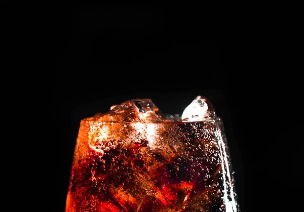 Cola and ice in a glass on black background. — Stock Photo, Image