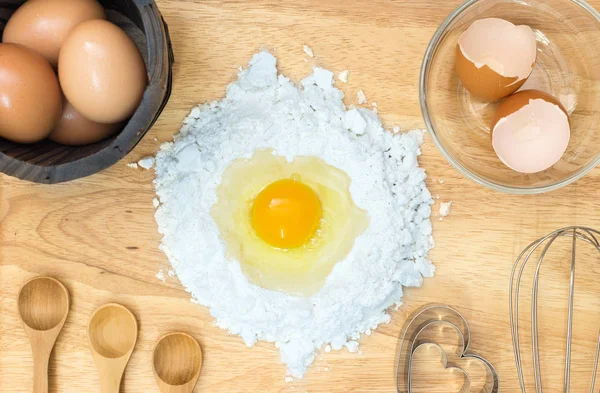 Zusammensetzung Mehl mit Ei und Zutaten für hausgemachte Backwaren auf Holzgrund — Stockfoto