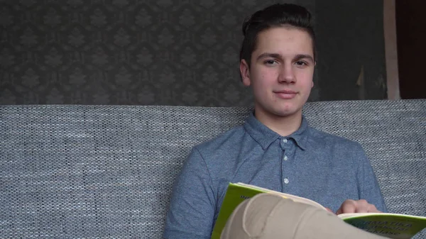 Chico Guapo Adolescente Lee Libro Sobre Sofá Gris Ojos Marrones — Foto de Stock