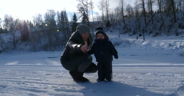 一个快乐美丽的母亲拥抱她的孩子 在滑雪胜地 在一个晴朗的日子 在冬天 所有在雪地里 — 图库视频影像