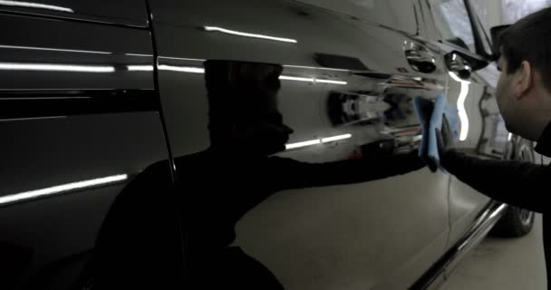 Έναν Επαγγελματία Ειδικό Σκουπίζει Ένα Γυαλισμένο Μαύρο Αυτοκίνητο Ένα Μπλε — Αρχείο Βίντεο