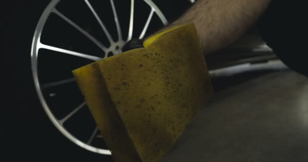 一个专业的专家持有黄色的海绵和喷雾 一辆黑色的汽车 — 图库视频影像