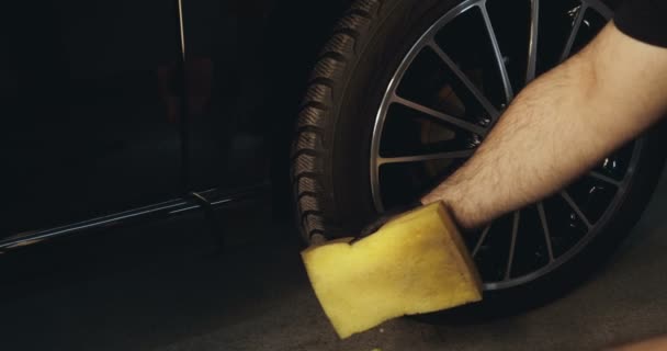一个专业的专家持有黄色的海绵和喷雾 一辆黑色的汽车 — 图库视频影像