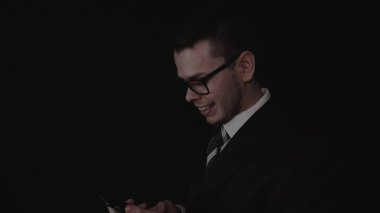 Bir takım elbise, siyah arka planda telefonda konuşurken gözlük, yakışıklı genç işadamı.