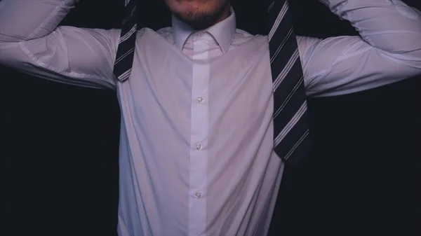 Businessman in white shirt, black background.