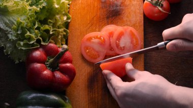 Mutfak masasında sebze, domates, kırmızı biber, zencefil, yeşil salata, petrol ve bıçak ile.