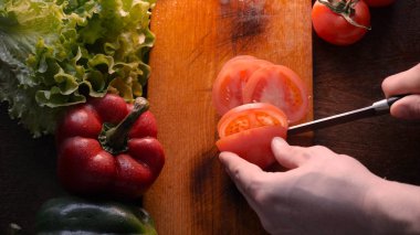 Mutfak masasında sebze, domates, kırmızı biber, zencefil, yeşil salata, petrol ve bıçak ile.