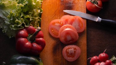 Mutfak masasında sebze, domates, kırmızı biber, zencefil, yeşil salata, petrol ve bıçak ile.