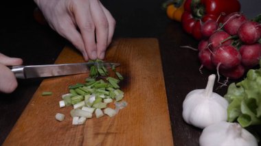 Mutfak masasında sebze, yeşil soğan, turp, kırmızı biber, yeşil salata, sarımsak ve bir bıçak ile.