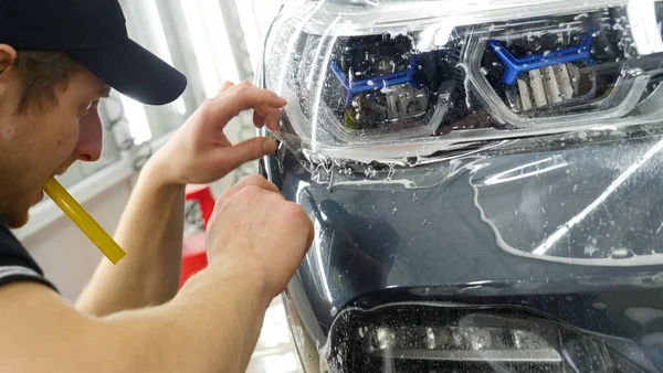 Ön far ve kaputta Ppf montaj işlemine yakın. Ppf, boyayı çizilmelerden ve taş yongalarından koruyan bir Boya Koruma Filmidir. Konsept: Koruma, Koruma, Araba, Yeni, İş.