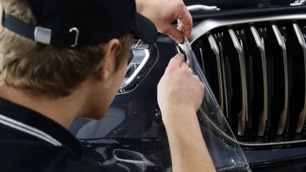 Ön far ve kaputta Ppf montaj işlemine yakın. Ppf, boyayı çizilmelerden ve taş yongalarından koruyan bir Boya Koruma Filmidir. Konsept: Koruma, Koruma, Araba, Yeni, İş.