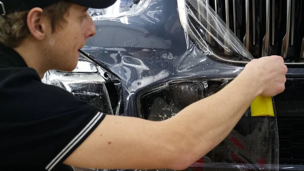 Close up to PPF installation process on a front headlight and hood