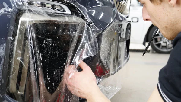 Ön far ve kaputta Ppf montaj işlemine yakın. Ppf, boyayı çizilmelerden ve taş yongalarından koruyan bir Boya Koruma Filmidir. Konsept: Koruma, Koruma, Araba, Yeni, İş.