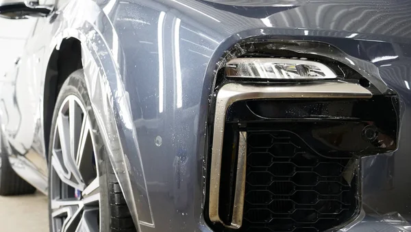 Ön far ve kaputta Ppf montaj işlemine yakın. Ppf, boyayı çizilmelerden ve taş yongalarından koruyan bir Boya Koruma Filmidir. Konsept: Koruma, Koruma, Araba, Yeni, İş.