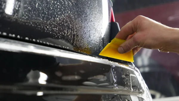 Ön far ve kaputta Ppf montaj işlemine yakın. Ppf, boyayı çizilmelerden ve taş yongalarından koruyan bir Boya Koruma Filmidir. Konsept: Koruma, Koruma, Araba, Yeni, İş.