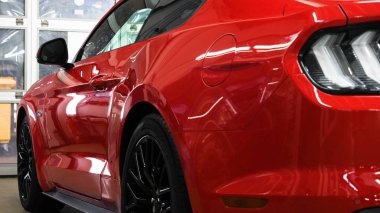 Garajda bir adam (araba servisi) kırmızı spor araba alarmını kontrol eder ve arkasından ışıkları kapatarak (içeri girer) kapanır. Otomobil garajı, Güvenlik kavramı.