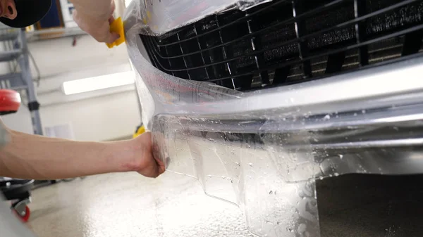 Ön far ve kaputta Ppf montaj işlemine yakın. Ppf, boyayı çizilmelerden ve taş yongalarından koruyan bir Boya Koruma Filmidir. Konsept: Koruma, Koruma, Araba, Yeni, İş.