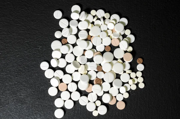Handvol pillen op een zwarte achtergrond-closeup — Stockfoto