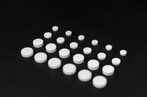 Tabletten bekleed in rijen op een zwarte achtergrond, verschillende grootte, close-up — Stockfoto