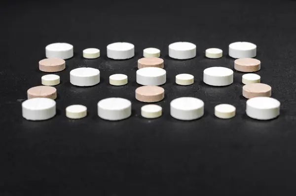 Tabletter fodrad i rader på en svart bakgrund — Stockfoto