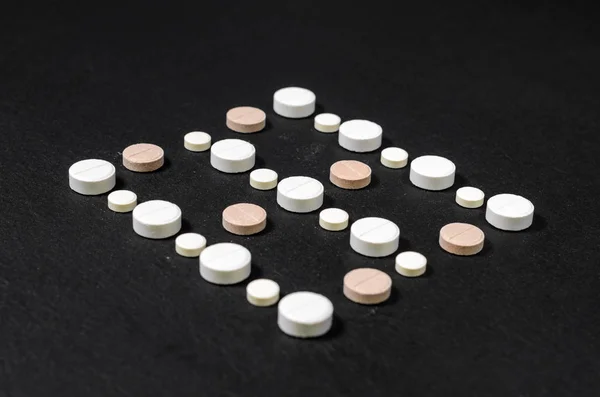 Tabletten bekleed in rijen op een zwarte achtergrond — Stockfoto