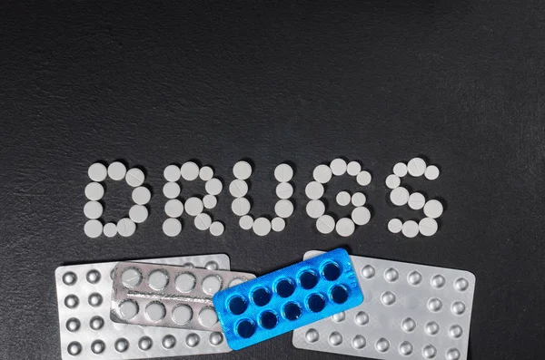 The word "drugs" is laid out of pills on a dark background — Stock Photo, Image