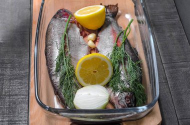 Baharat, ot ve bir pişirme çanağı, limon ile ham alabalık görünümü top