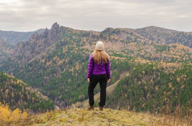 Bulutlu bir günde bir leylak ceket bekliyor bir dağ, bir görünümü bir sonbahar orman ve dağlar bir kız
