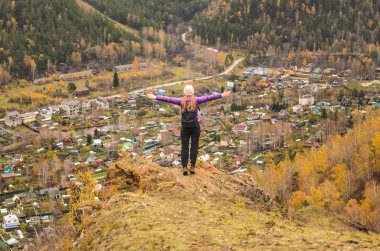 Bir kız leylak ceket kollarında bir dağ, bir görünümü bir sonbahar orman ve dağlar bir bulutlu gün tarafından germe boş alan metin için