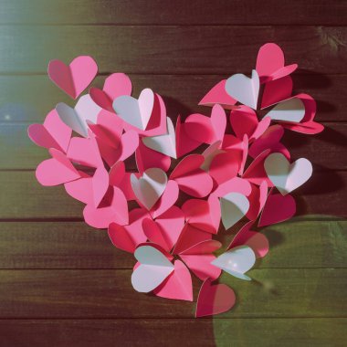 Kağıttan ortaya konulan kırmızı kalpler büyük kalp üstten görünüm şeklinde kesip