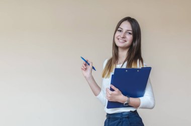 Mavi klasörünü ve metin için boş alan ile hafif bir arka plan üzerinde kalem ile genç esmer kız.