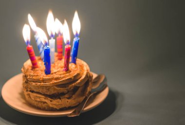 Krem ve çok karanlık bir arka plan üzerinde mumlar yanan ile çikolatalı kek.