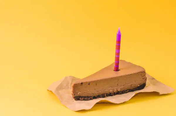 黄色の背景にライラックの蝋燭とチョコレートのチーズケーキの部分をクローズ アップ — ストック写真
