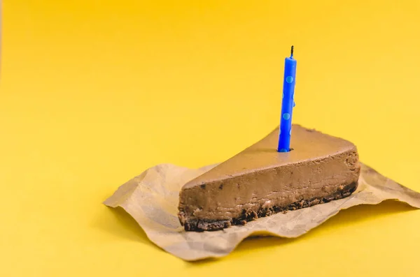 黄色の背景に青いキャンドル チョコレート チーズケーキの部分をクローズ アップ — ストック写真