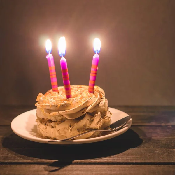 Krem ve karanlık bir arka plan üzerinde üç yanan mumlar ile çikolatalı kek