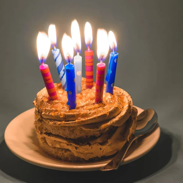 Krem ve çok karanlık bir arka plan üzerinde mumlar yanan ile çikolatalı kek.