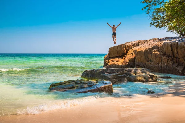 A boldog fiatalember, leugranak a szikláról az óceánba — Stock Fotó