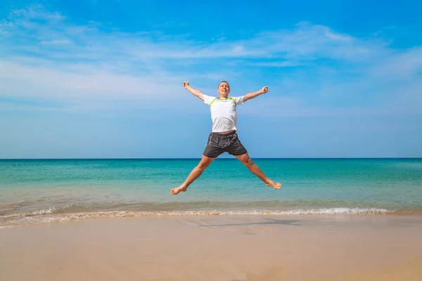 Homem turístico feliz pulando em uma praia tropical — Fotografia de Stock