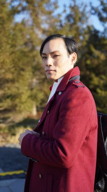 Güneşli bir günde Moskova 'nın merkezinde yürürken dışarıda poz veren kırmızı ceketli çekici bir adamın portresi.