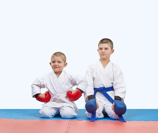 Two boys athletes in red and blue overlays sit on the mats — Stock Photo, Image