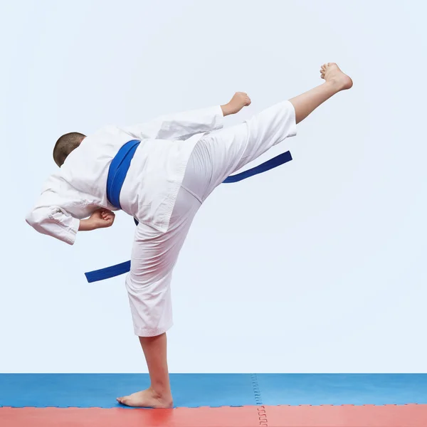 No tatami vermelho e azul o atleta de karatê bate chutando — Fotografia de Stock