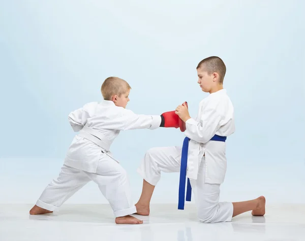 Chłopiec karateka bije punch na fitness maszyny że brat trzyma — Zdjęcie stockowe