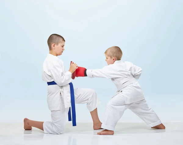 Con sovrapposizioni su mani karateka in karate gi batte pugno su simulatori — Foto Stock