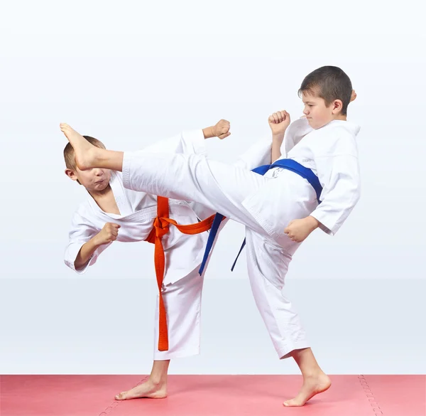 Zwei Karateka schlagen Tritte auf den roten Matten — Stockfoto