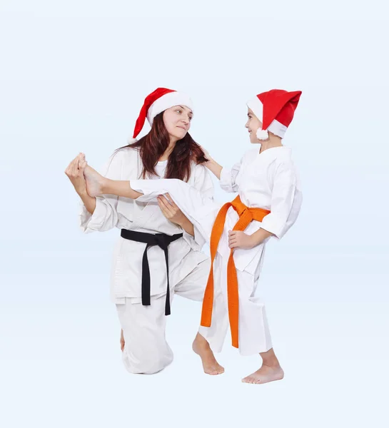 Família de esportes em bonés de Papai Noel estão treinando perna pontapé — Fotografia de Stock