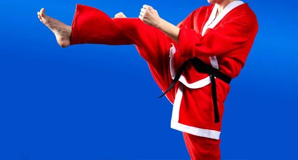 Auf blauem Hintergrund schlägt Karateka im Anzug des Weihnachtsmannes — Stockfoto