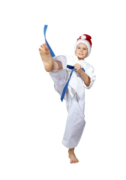 A boy with a blue belt and a cap of Santa Claus hits a kick leg — Stock Photo, Image