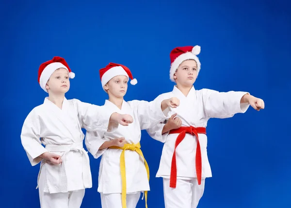 Em gorros de Papai Noel três atletas batem no braço de soco — Fotografia de Stock