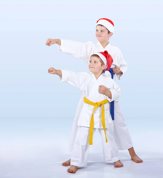 W karategi i kapelusze Santa Claus sportowców biją ramię dziurkacza — Zdjęcie stockowe